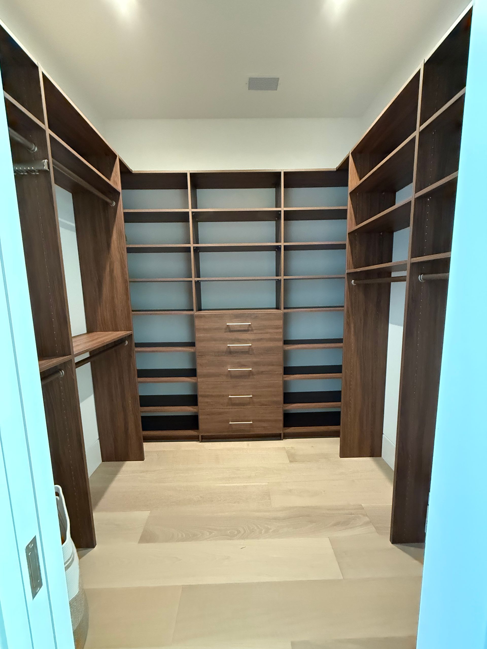 A walk in closet with lots of shelves and drawers