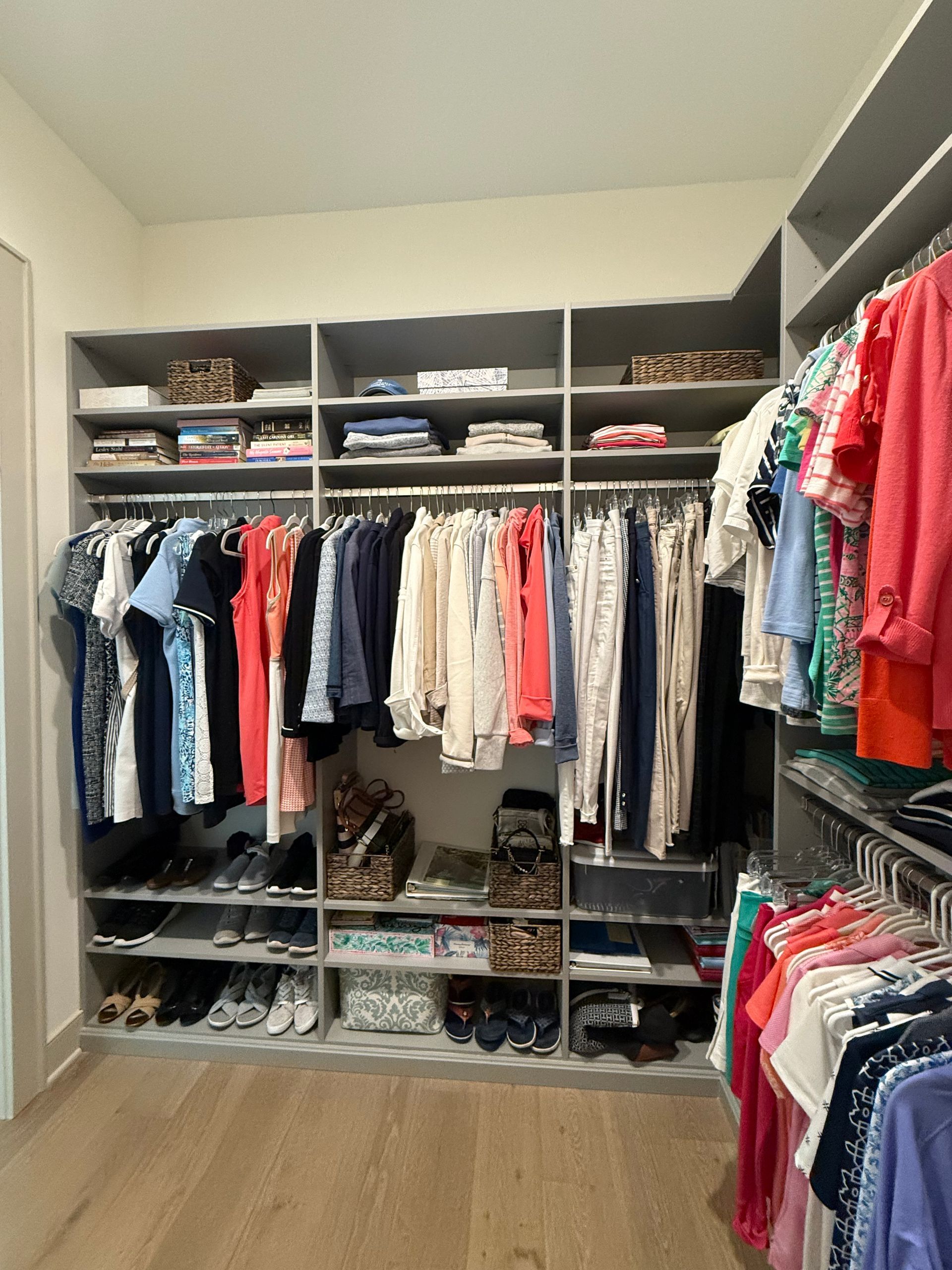 A walk in closet filled with lots of clothes and shoes.