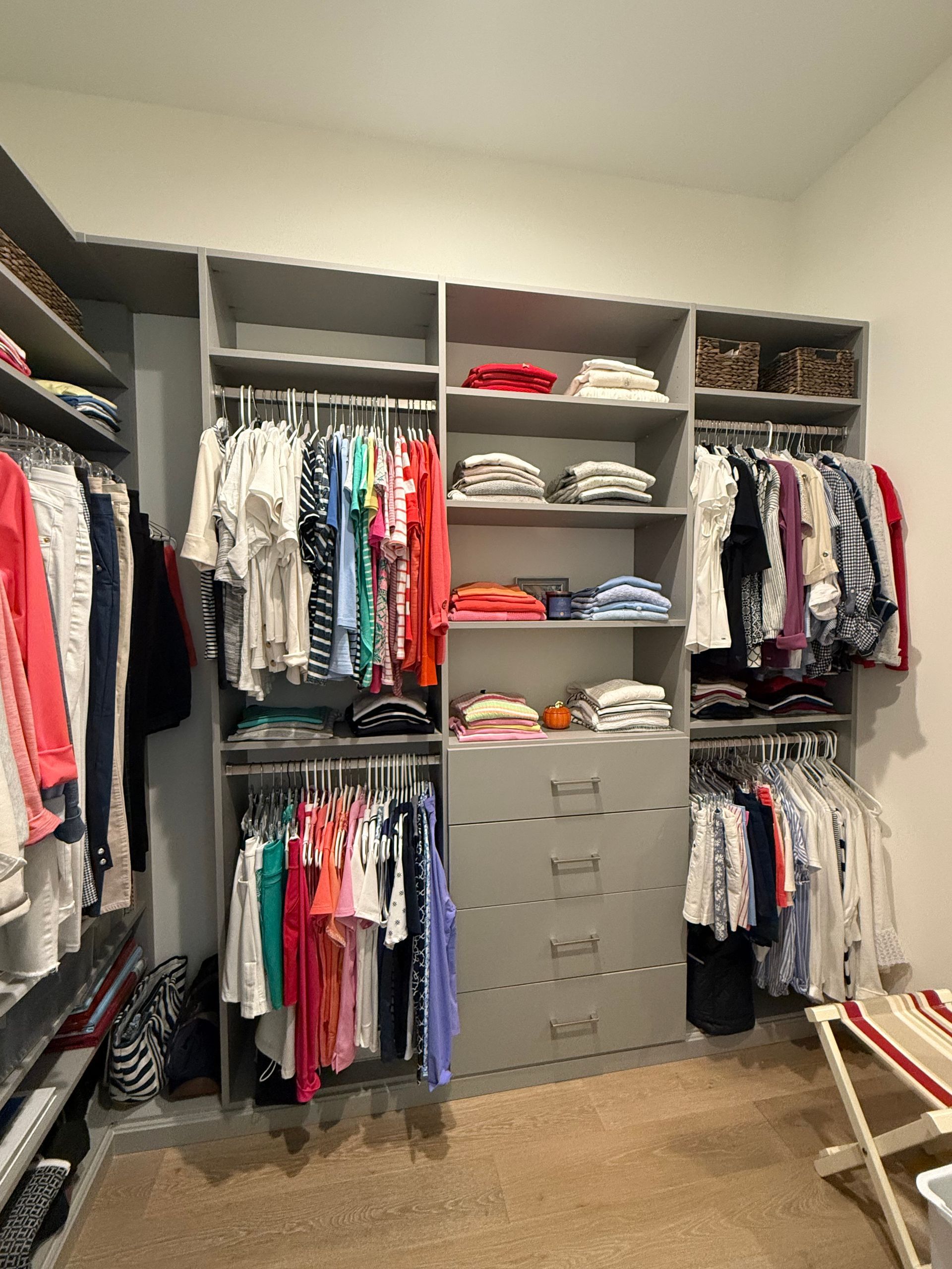 A walk in closet filled with lots of clothes and a chair.