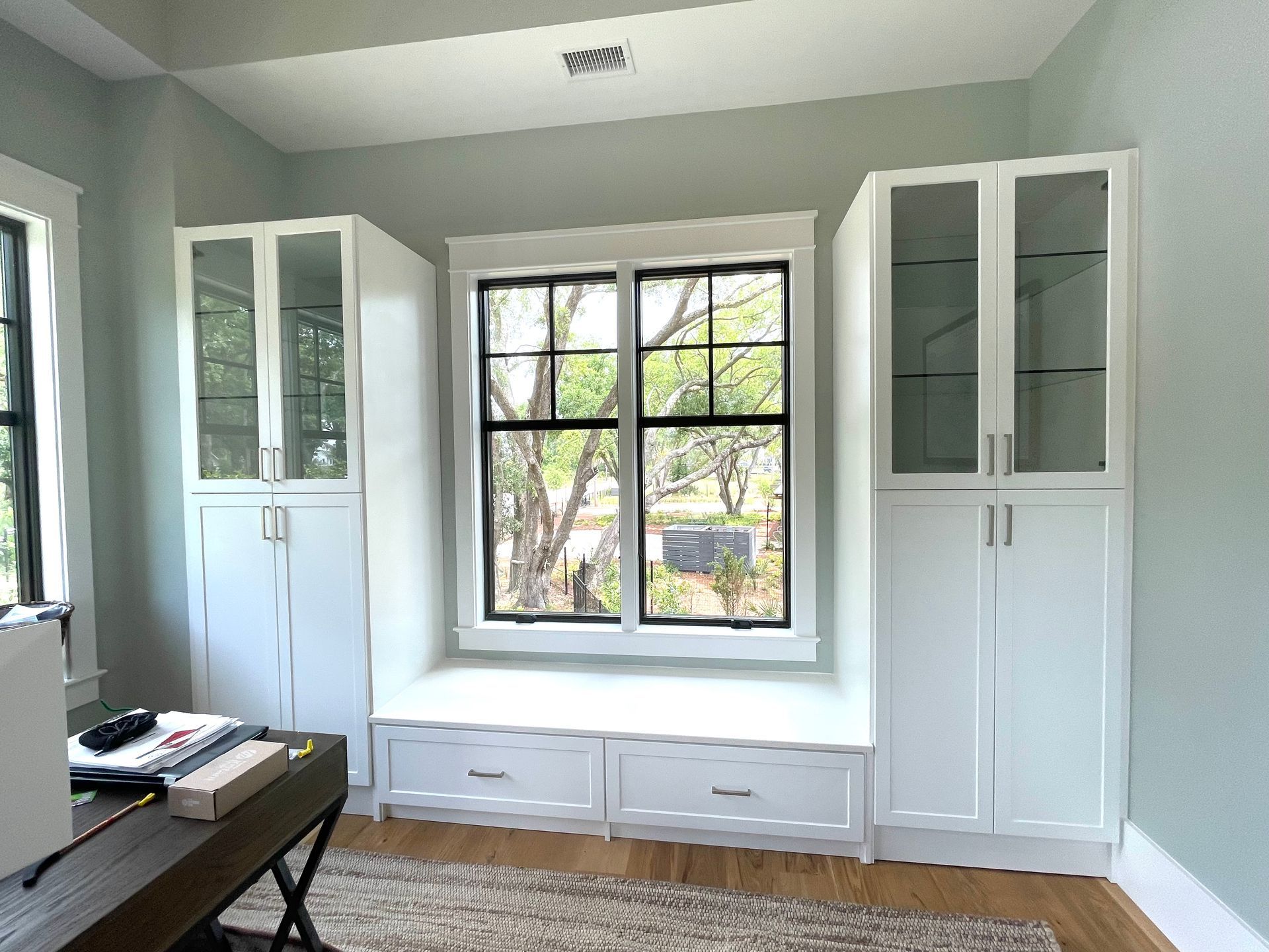 A living room with a window seat and white cabinets.