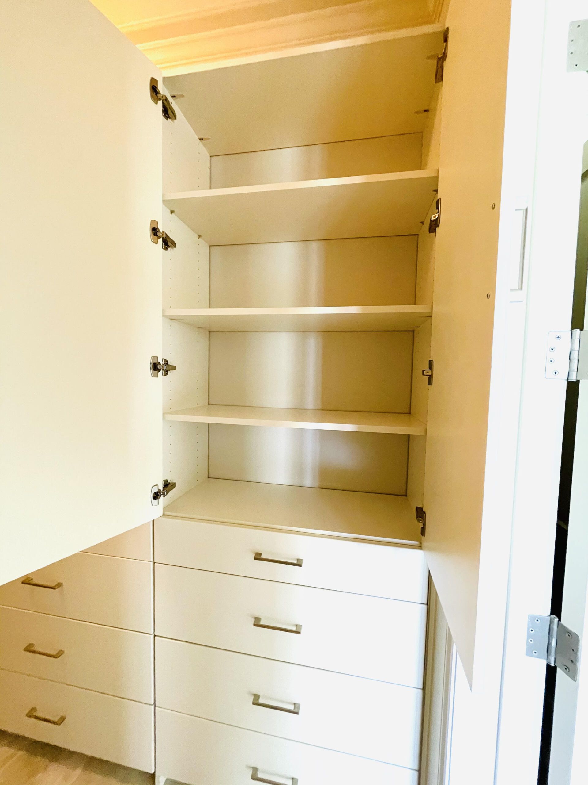 A closet with shelves and drawers and the door open