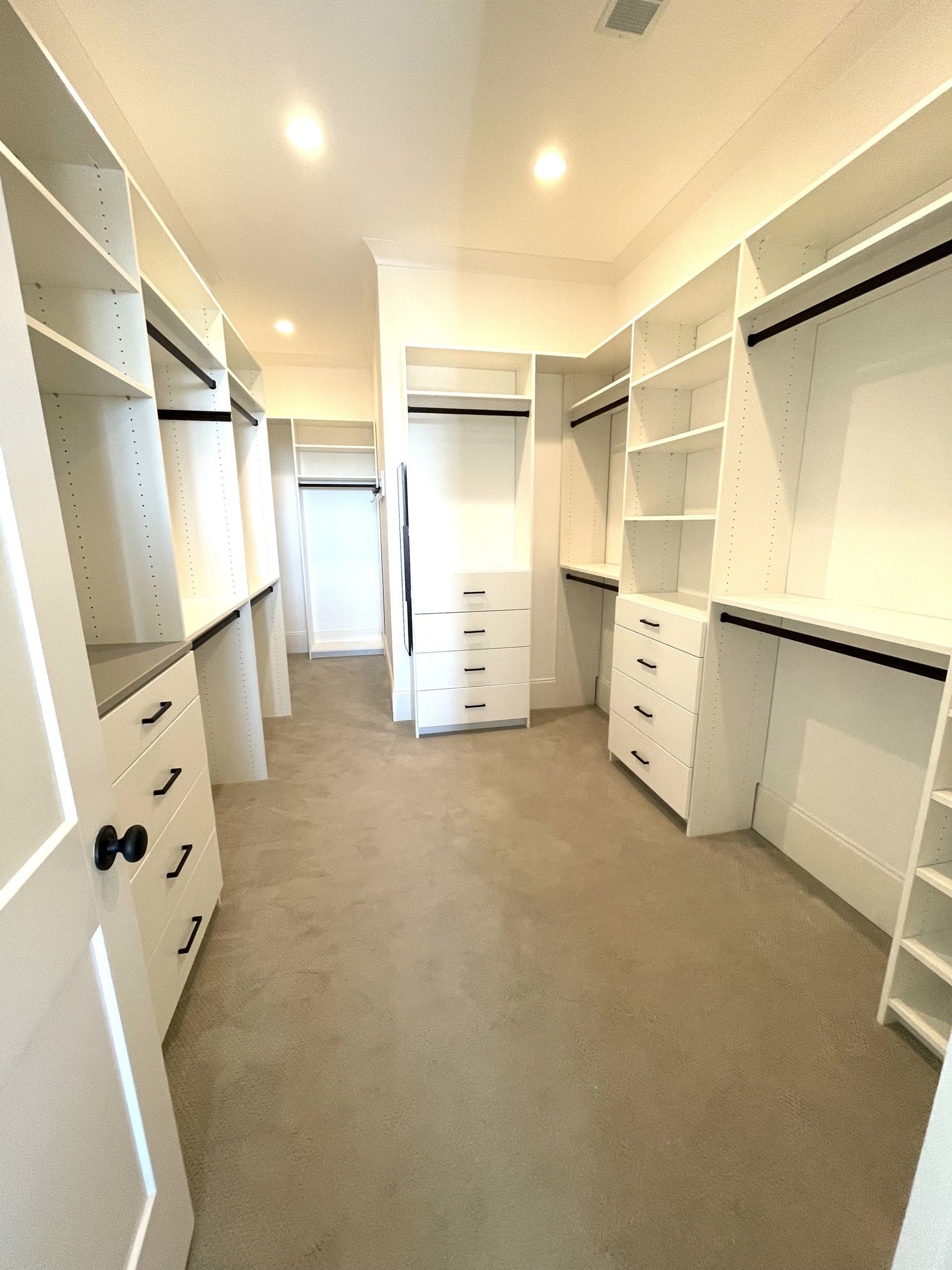 A walk in closet with lots of shelves and drawers.