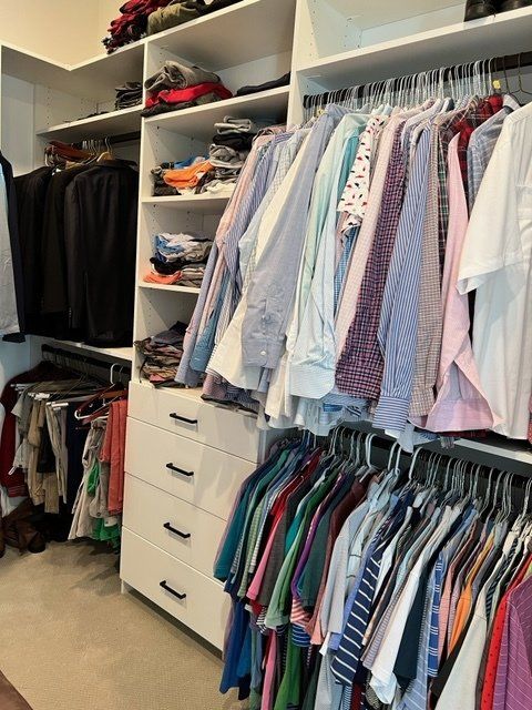 A closet filled with lots of clothes including shirts and ties