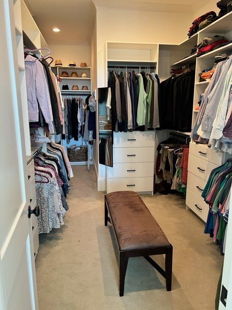 A walk in closet filled with clothes and a bench