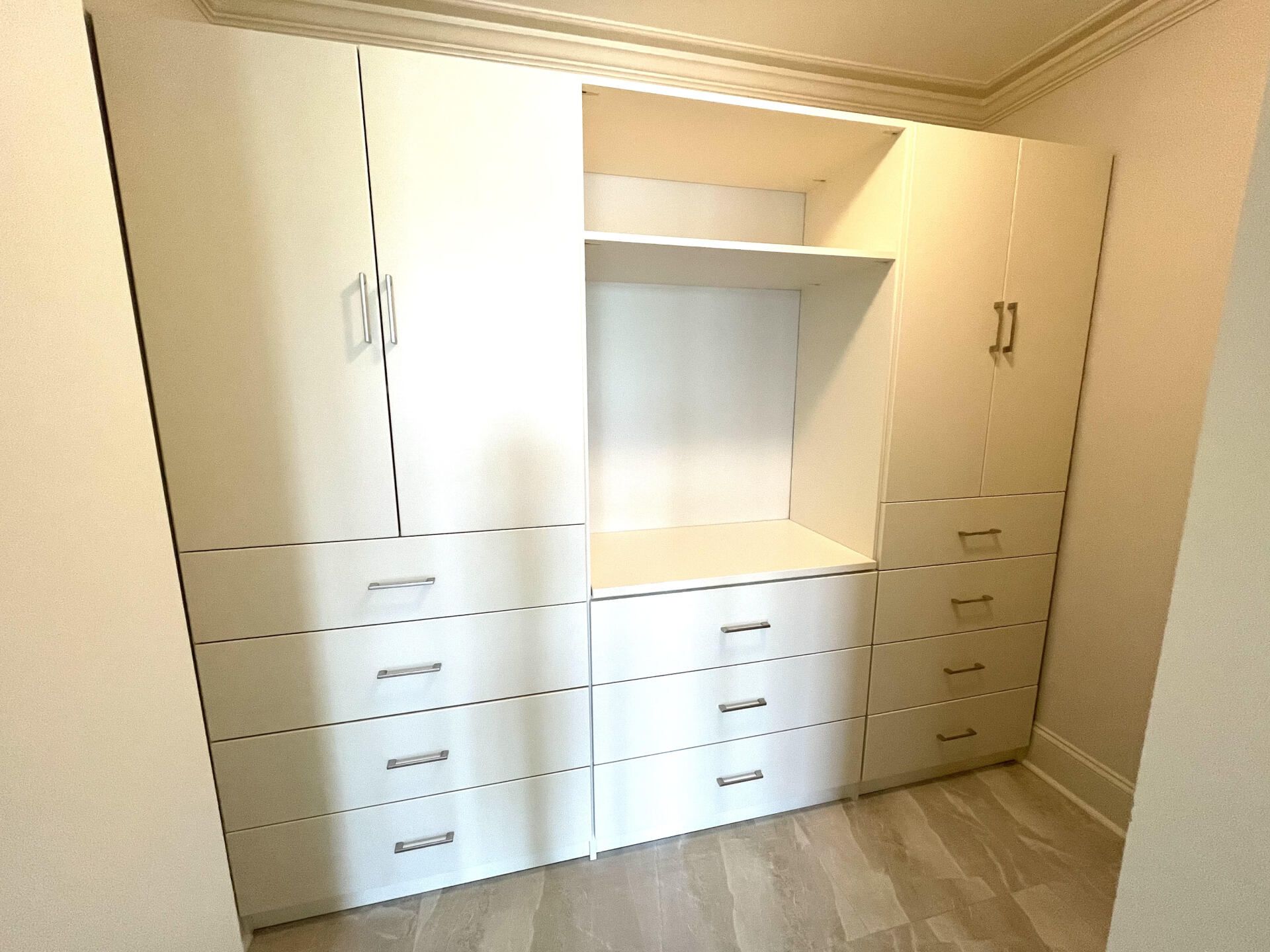 A room with a lot of white cabinets and drawers
