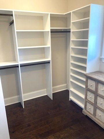 A walk in closet with lots of shelves and a dresser.