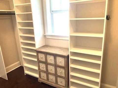 A walk in closet with lots of shelves and drawers and a window.