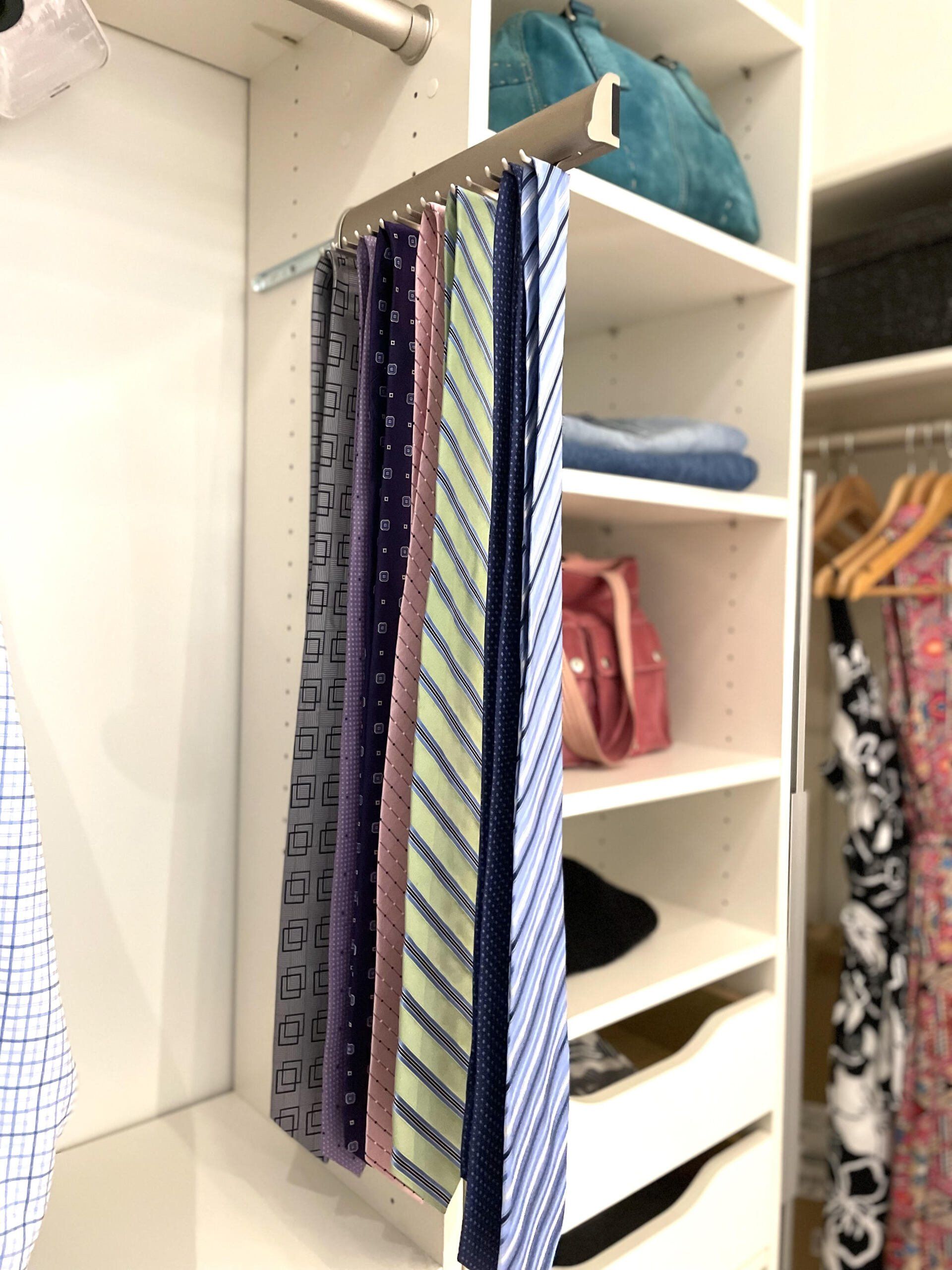 A bunch of ties are hanging on a rack in a closet