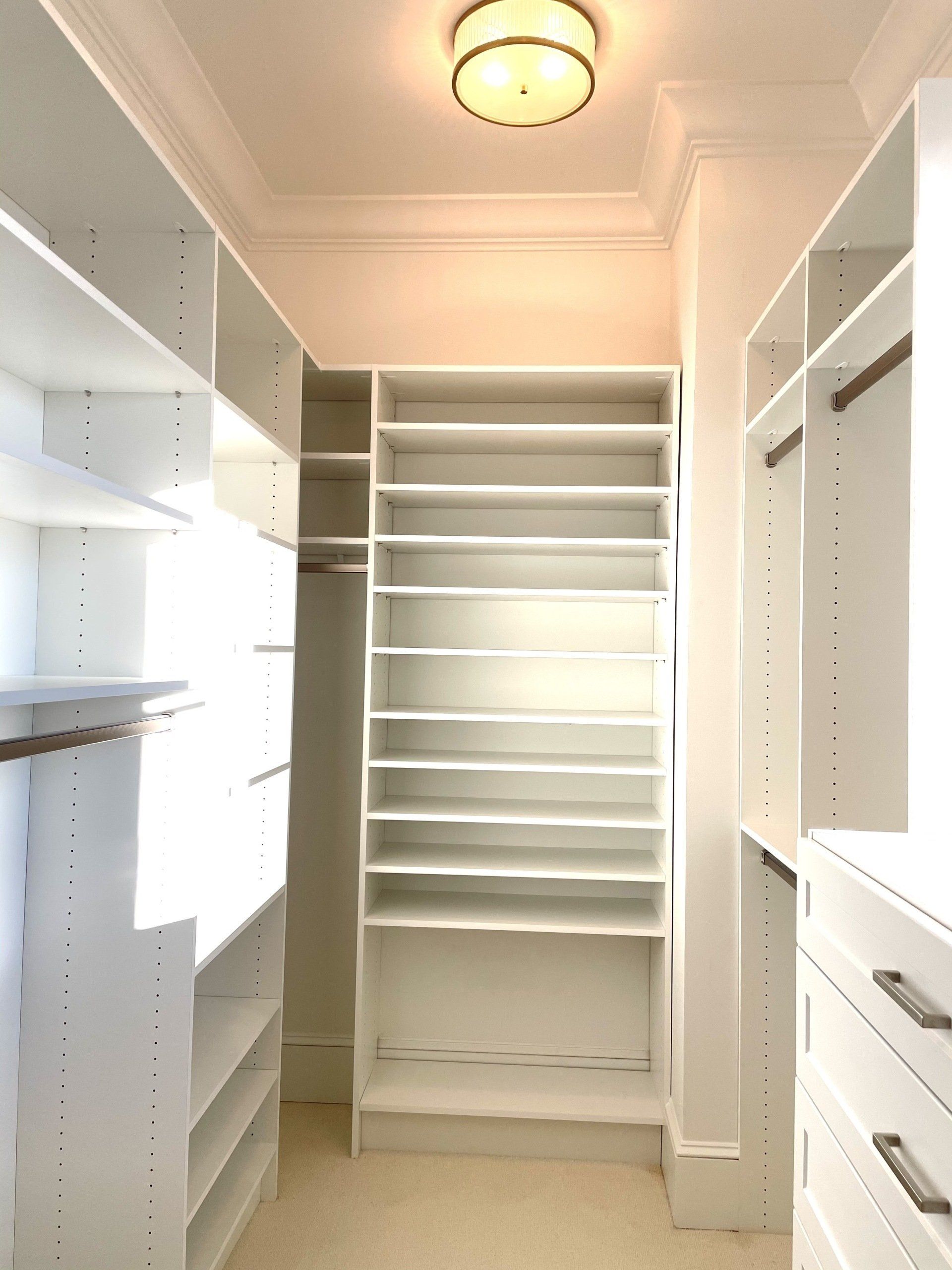 A walk in closet with lots of shelves and drawers