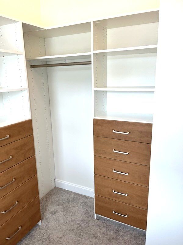A walk in closet with wooden drawers and shelves.