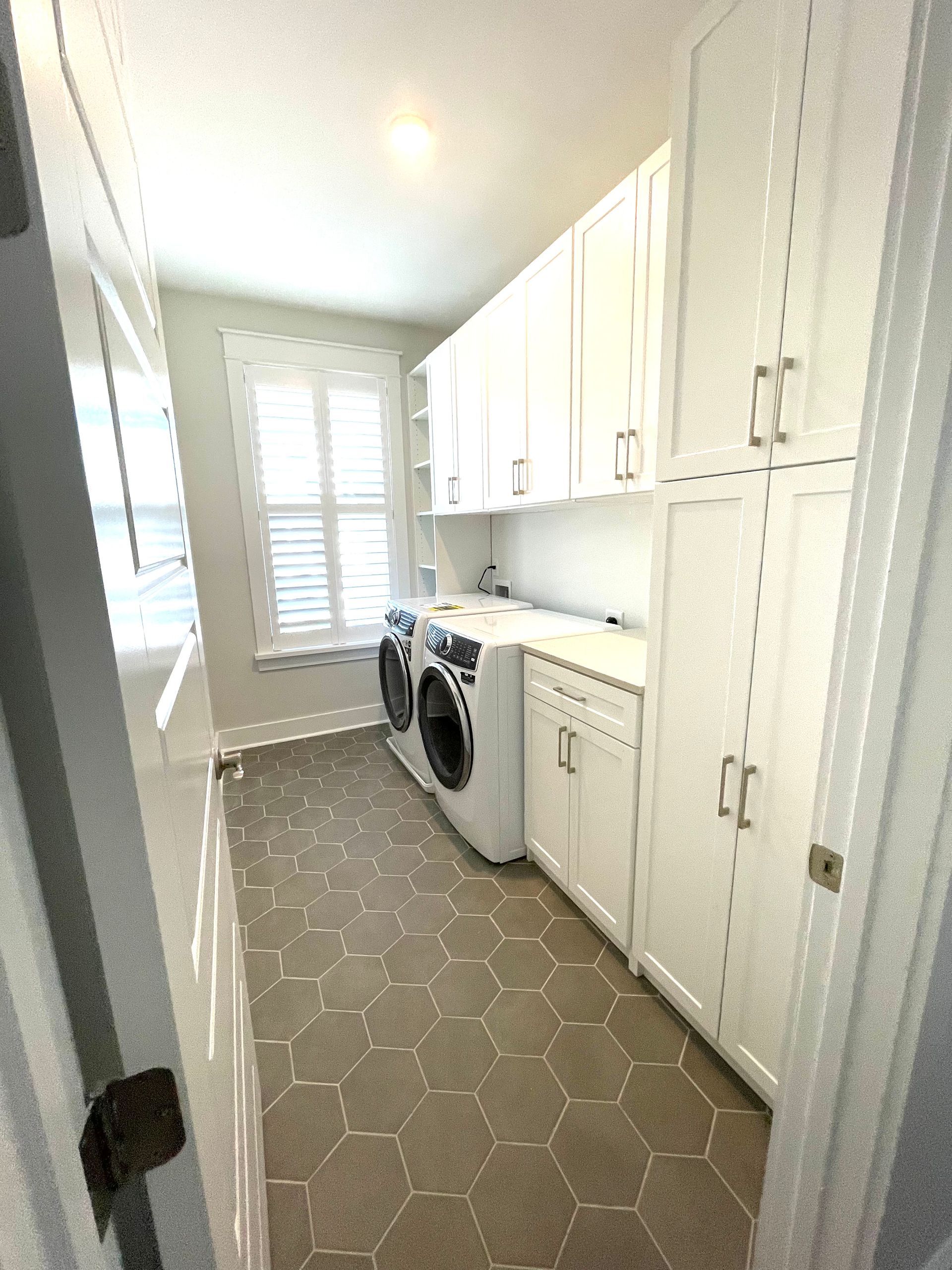 A laundry room with a washer and dryer and white cabinets.