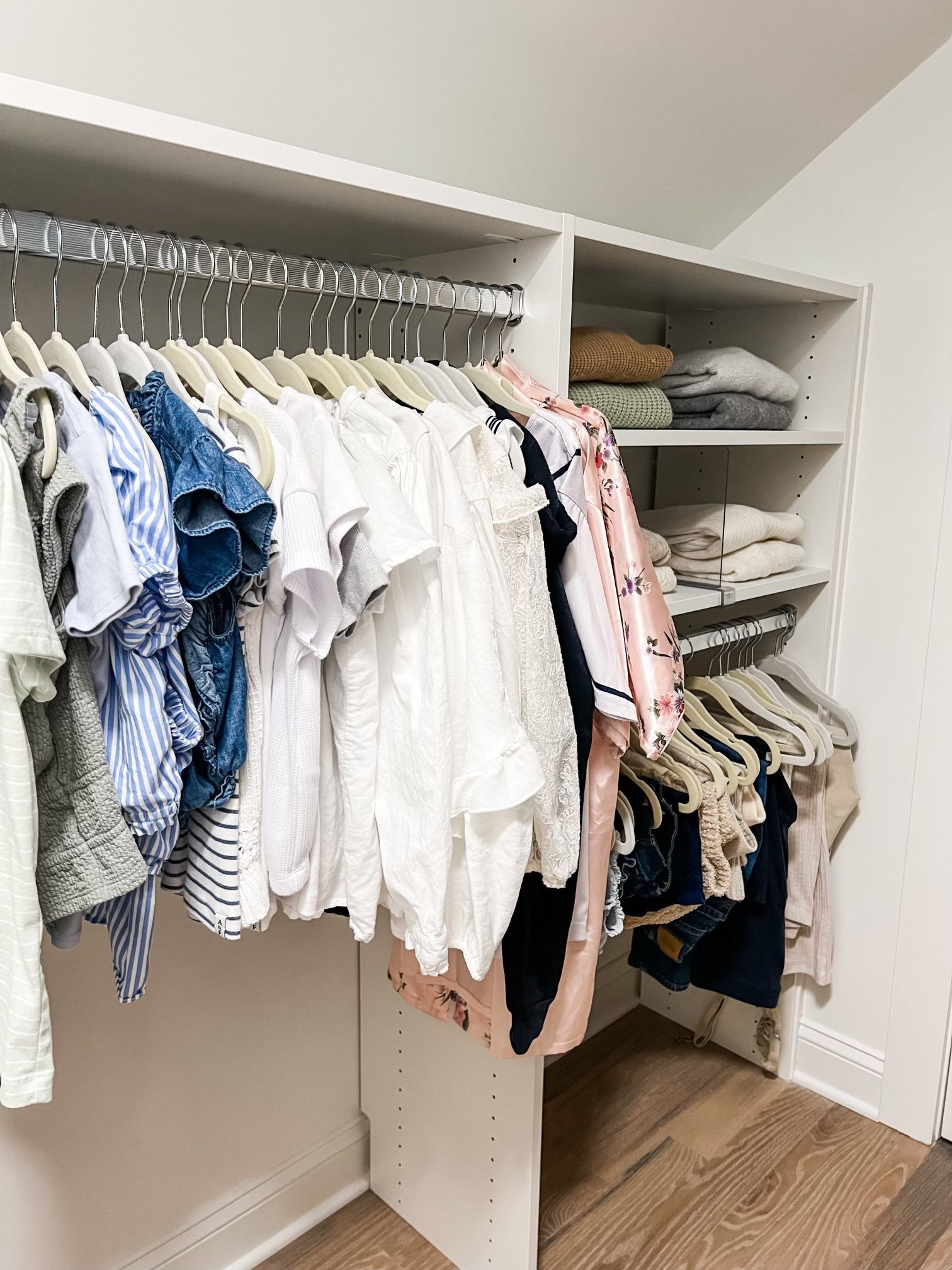 A closet filled with lots of clothes hanging on racks.