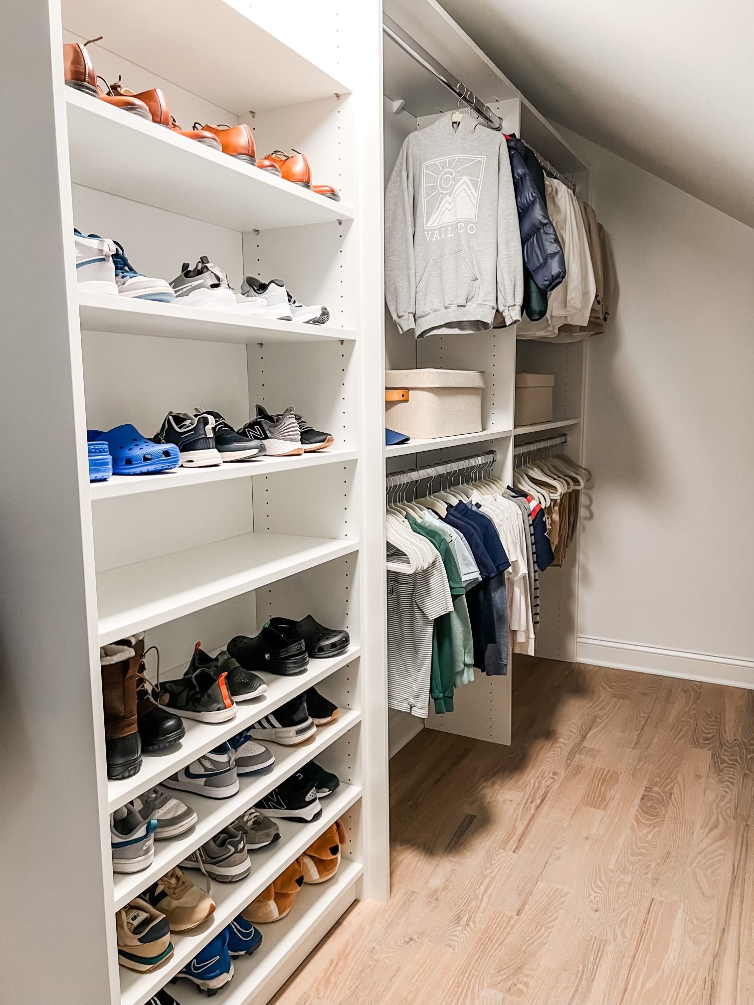 A walk in closet with shelves filled with shoes and clothes.