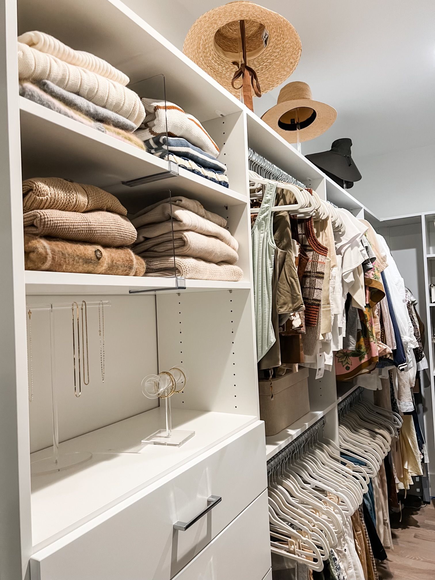 A walk in closet filled with clothes and hats.
