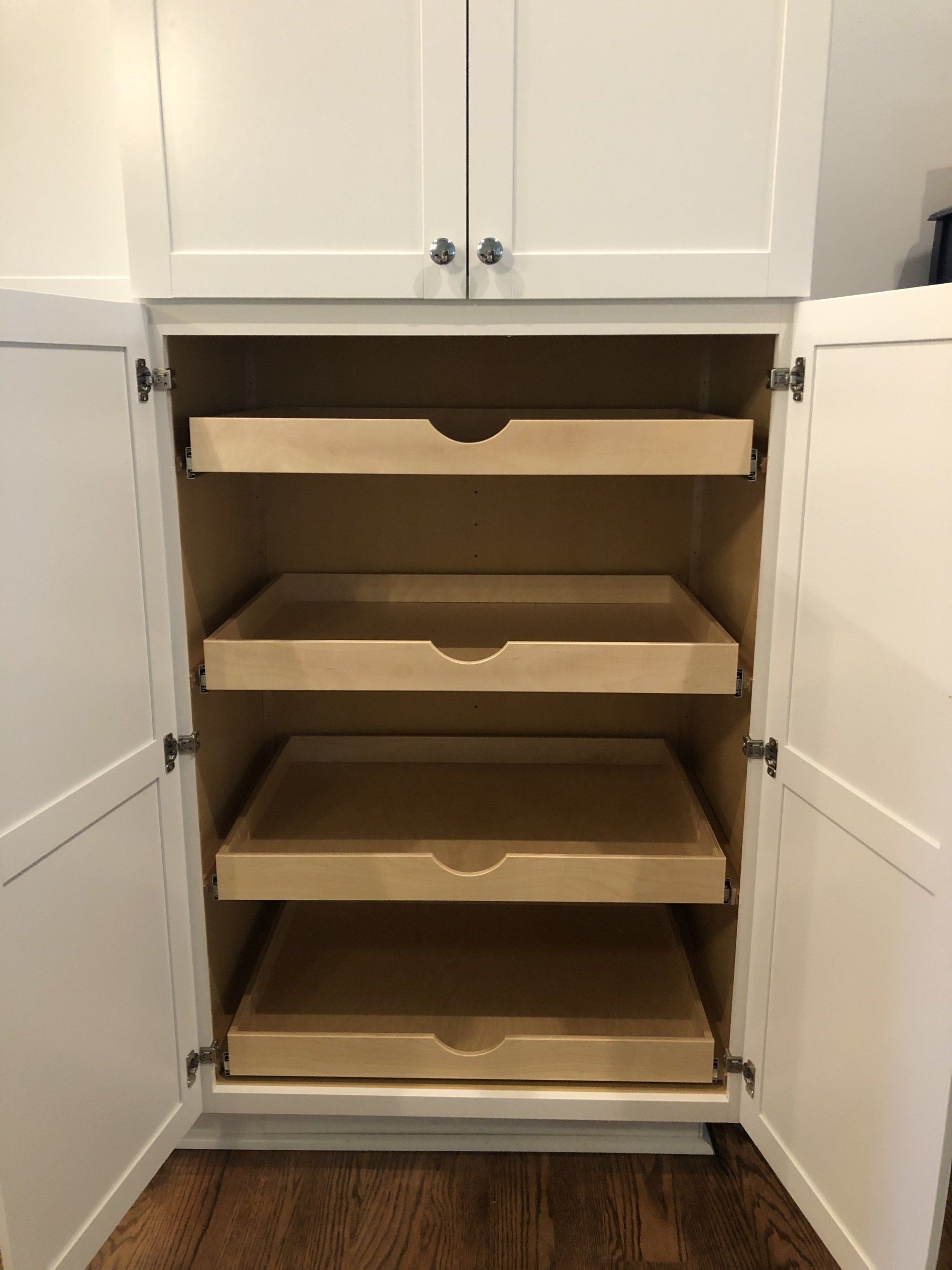 The inside of a cabinet with the doors open and three drawers.