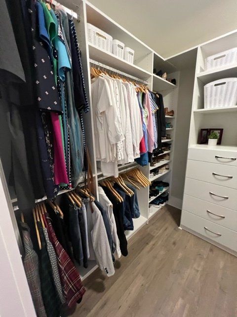 A walk in closet filled with clothes and a dresser