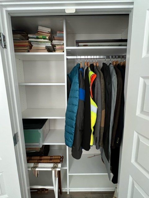 A closet with clothes hanging on a rack and shelves