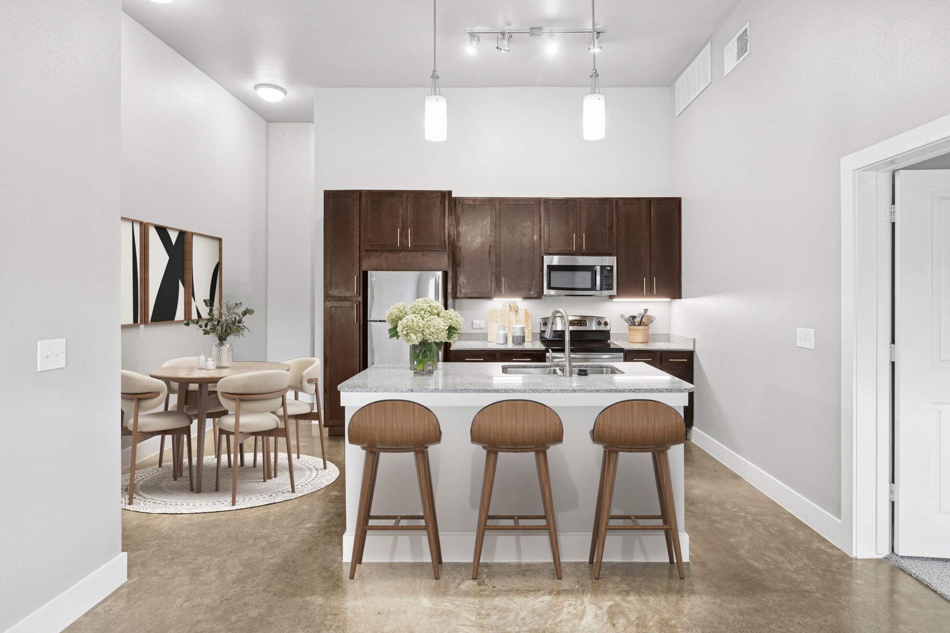 Modern kitchen with island seating three, dark wood cabinets, stainless steel appliances, and adjacent dining area.
