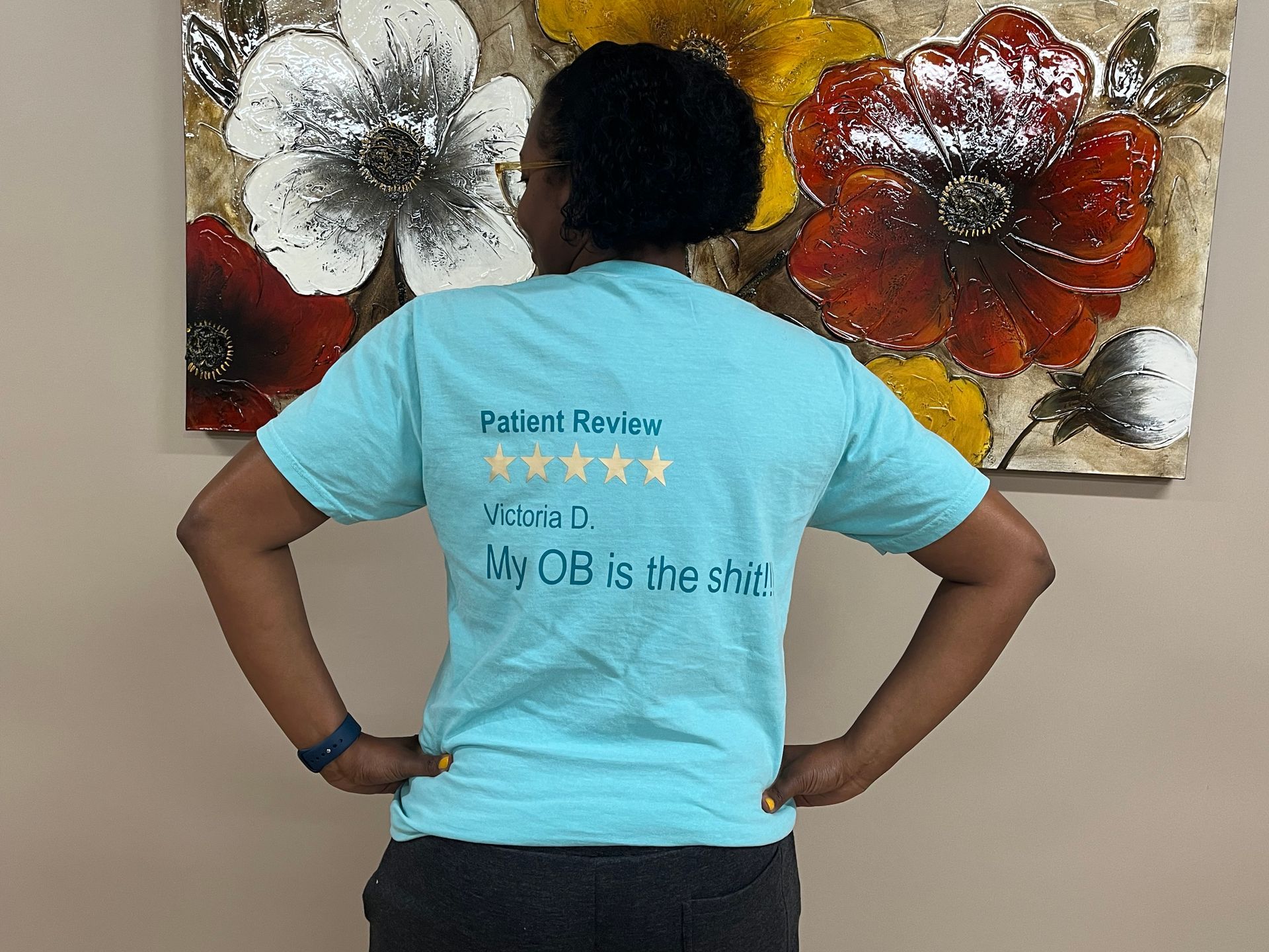 A woman is standing in front of a painting of flowers.