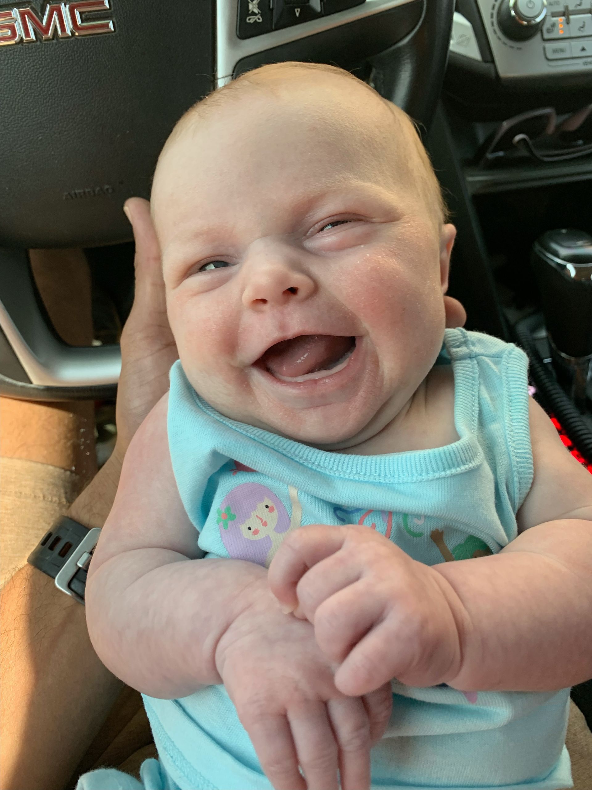 A baby is being held in a car.