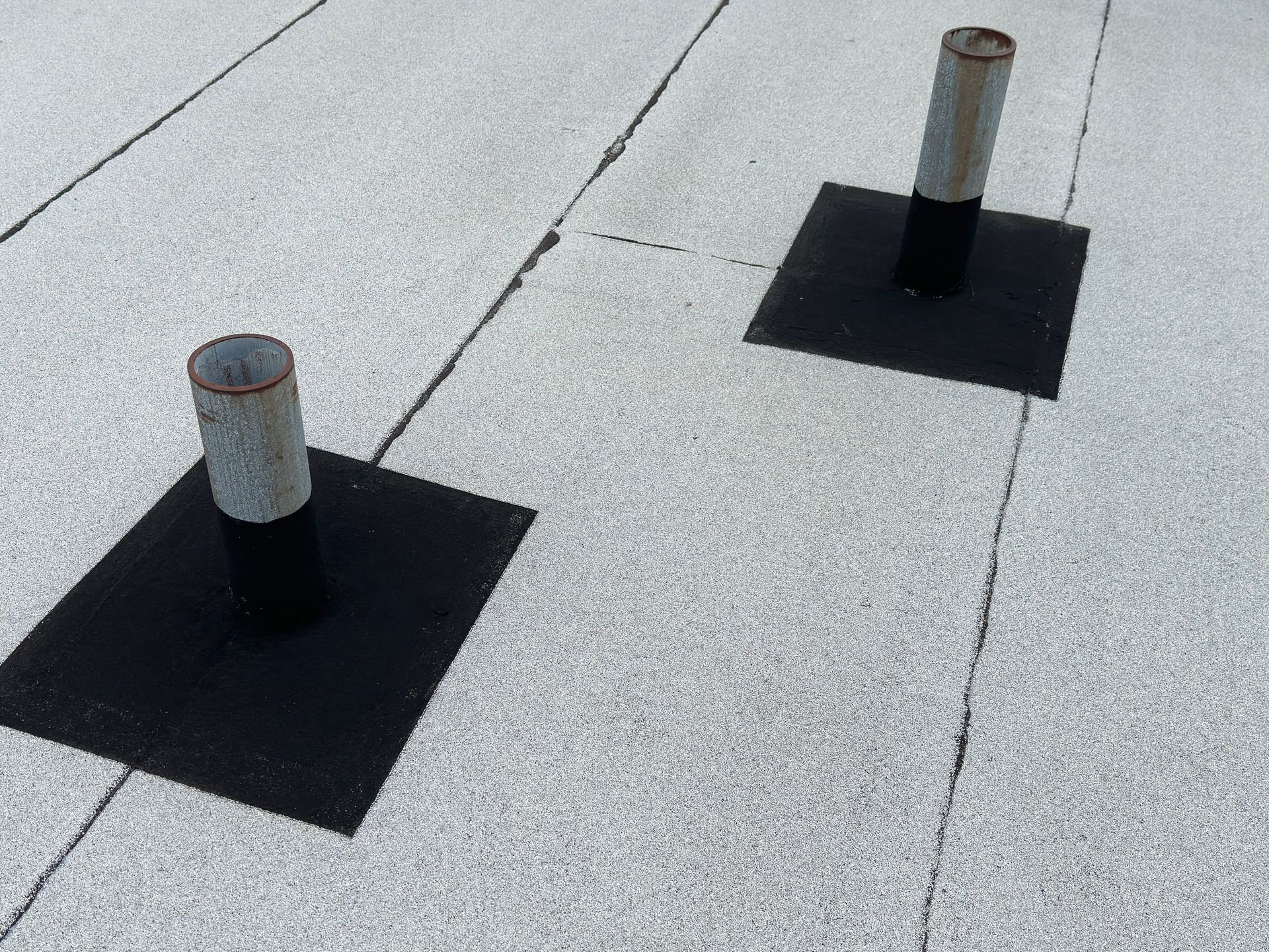 Flat roof surface with sewer vents, highlighting flat roof repair. Flat roof surface with sewer vents, highlighting flat roof repair.