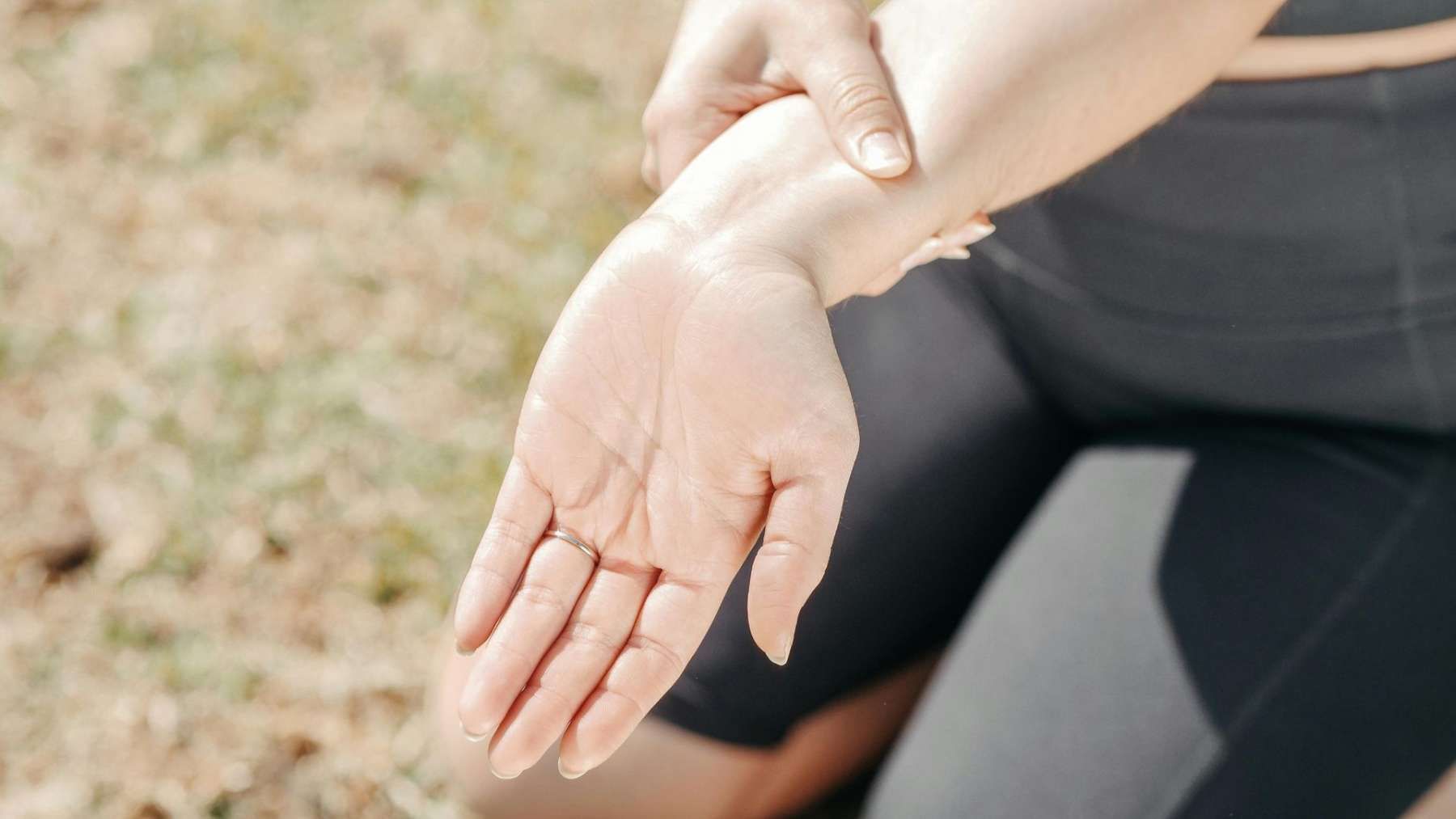 A woman extends her hand outward, showcasing symptoms of hand swelling and seeking relief through gentle stretching.