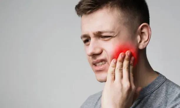 A man experiences a toothache, visibly pained, with shingles appearing on his neck and face.