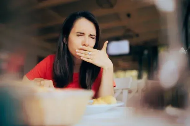 A woman at a table, mouth agape, expressing astonishment while sharing her story about shingles.