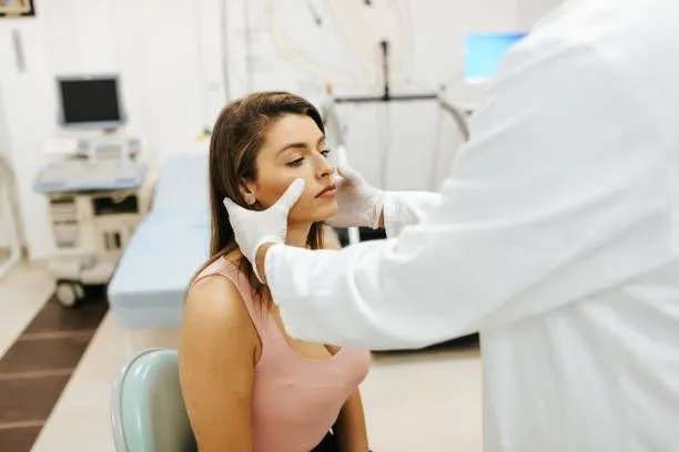 Doctor examining a woman's face in a medical office.