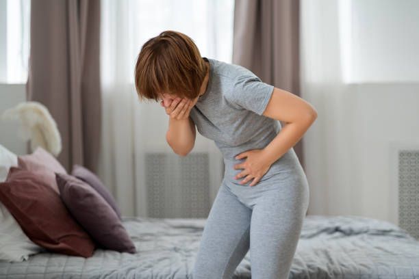 A woman holding her stomach due to stomachache.