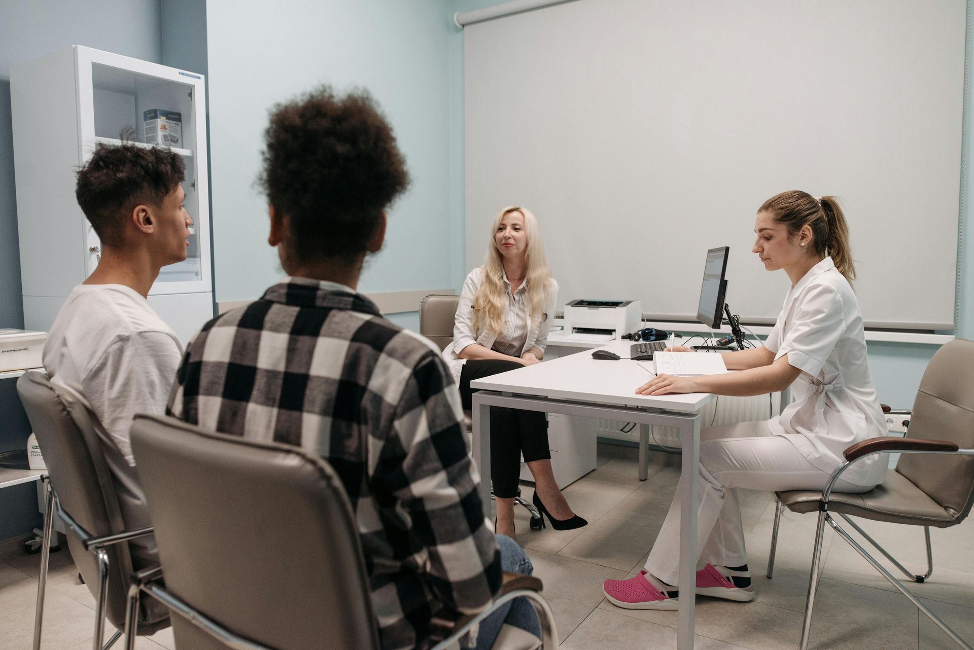 Two doctors talking to two patients inside an urgent care clinic.