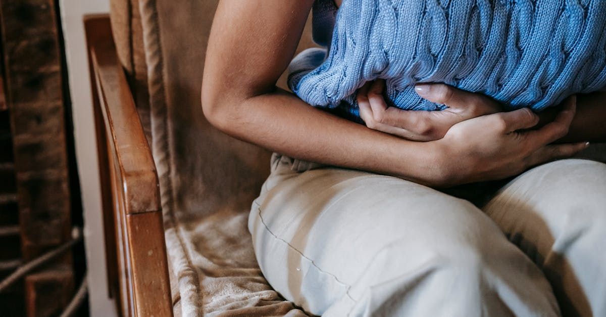 A woman is sitting in a chair holding her stomach in pain.