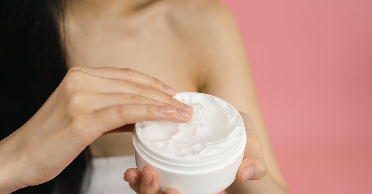 A woman is applying cream to her arm.