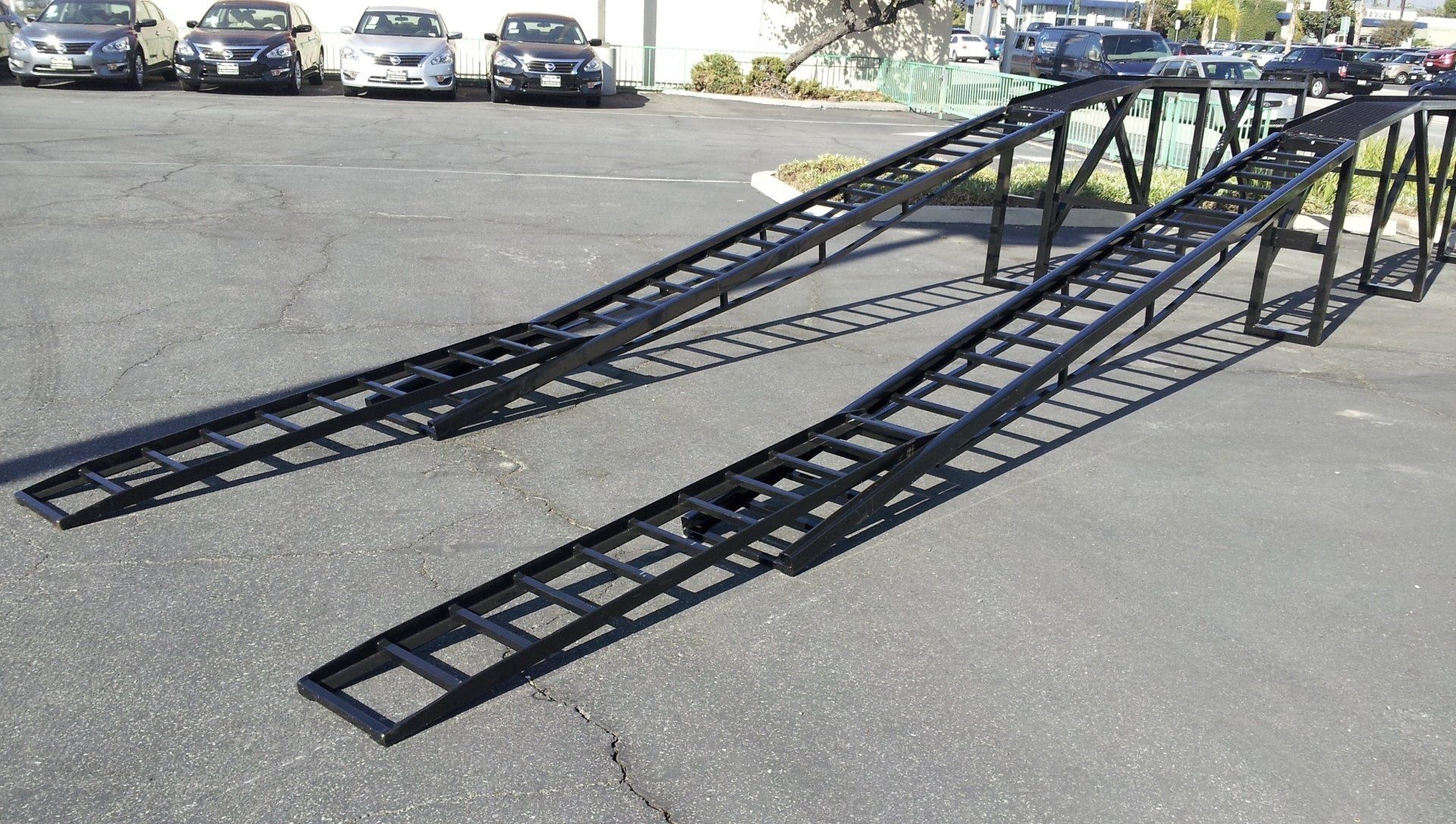 A car ramp is sitting in a parking lot with cars parked behind it