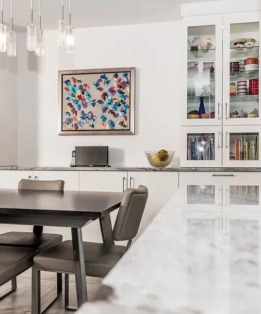 Cuisine moderne avec armoires blanches, œuvres d'art et table à manger.