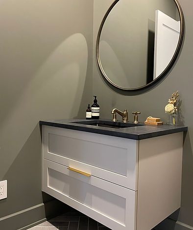 Meuble-lavabo de salle de bain moderne avec un miroir rond et du matériel doré.