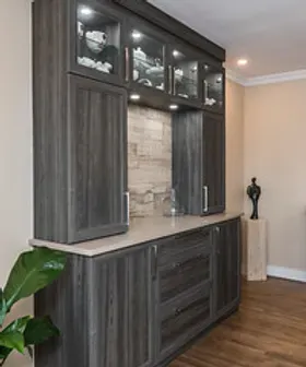 Meuble encastré gris foncé avec façades vitrées. La vitrine est dotée d'un dosseret beige et d'un plan de travail clair.