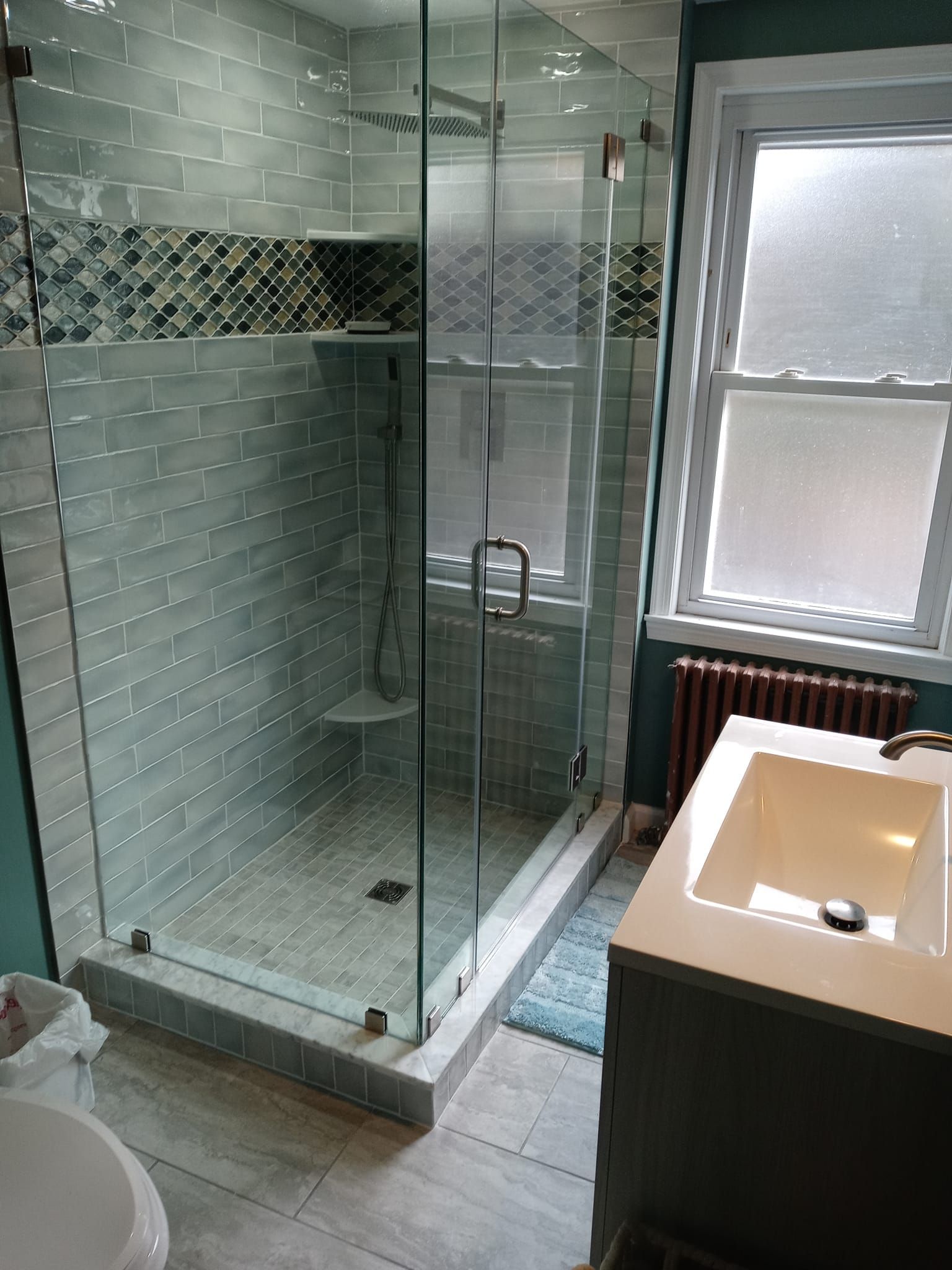 Bathroom with a glass shower enclosure, blue walls, white sink, and window.