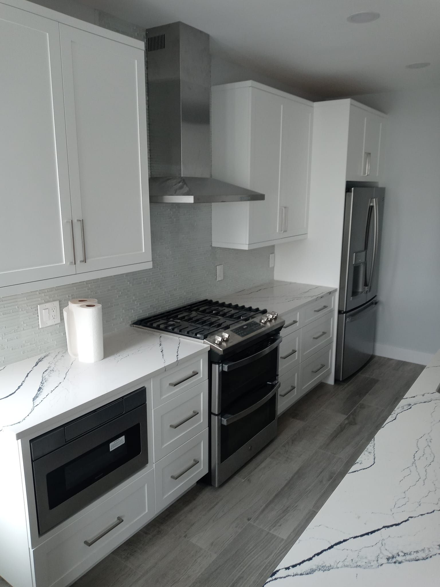 Modern kitchen with white cabinets, stainless steel appliances, and white countertops.