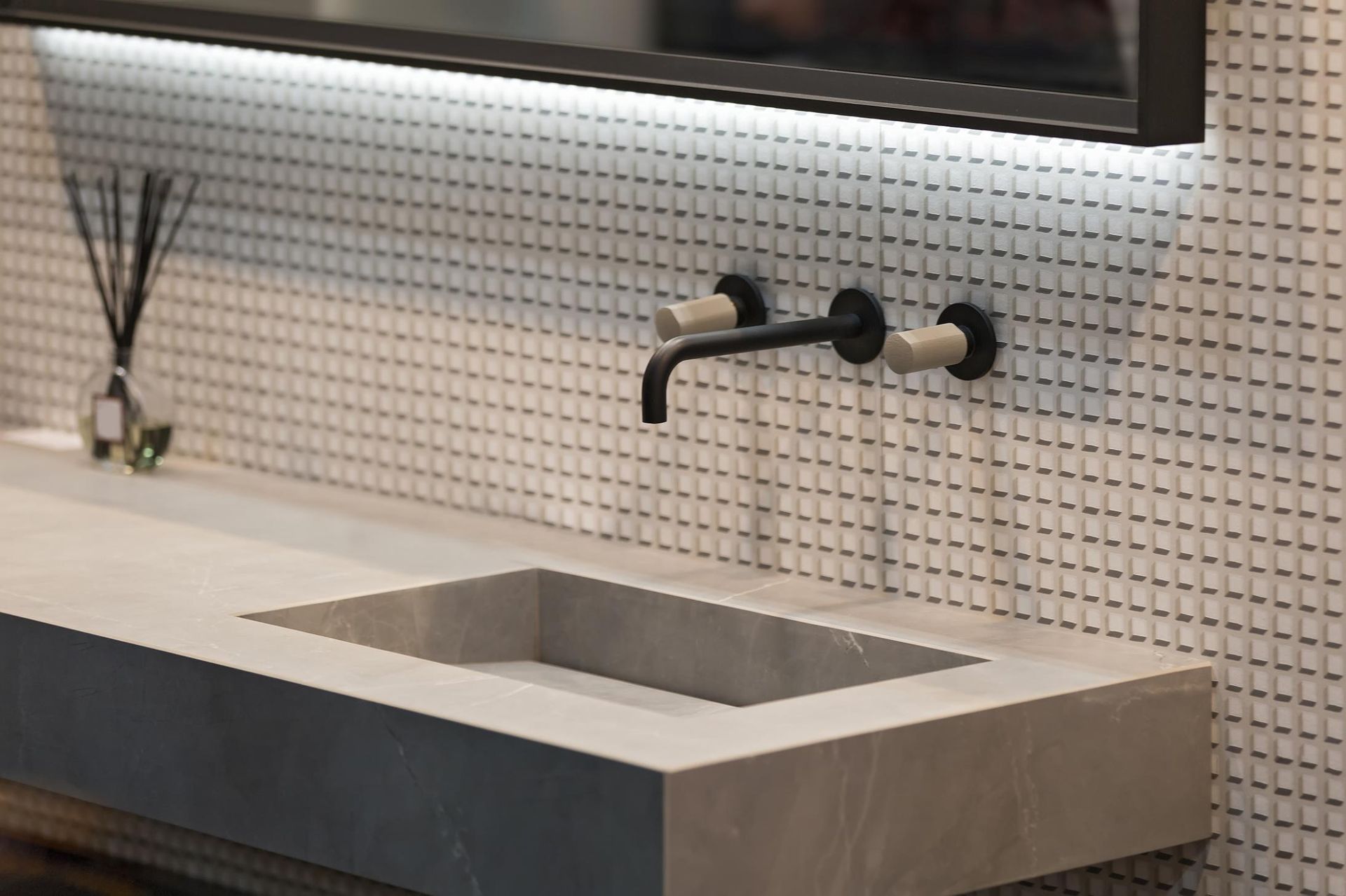 Bathroom sink with wall-mounted black faucet, gray countertop, square basin, and white tile backsplash.