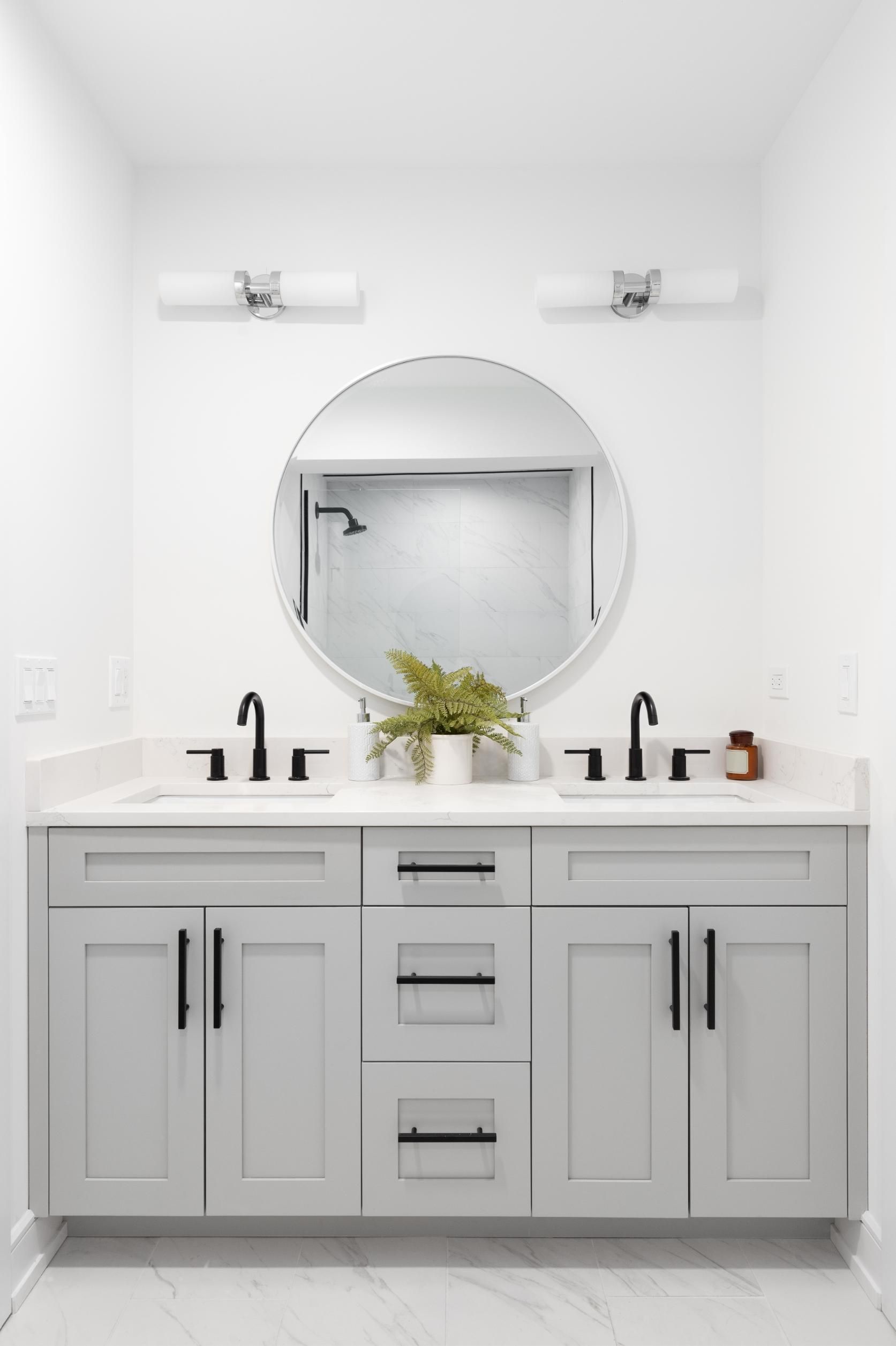 Light gray double bathroom vanity with black hardware, round mirror, and two sconces.