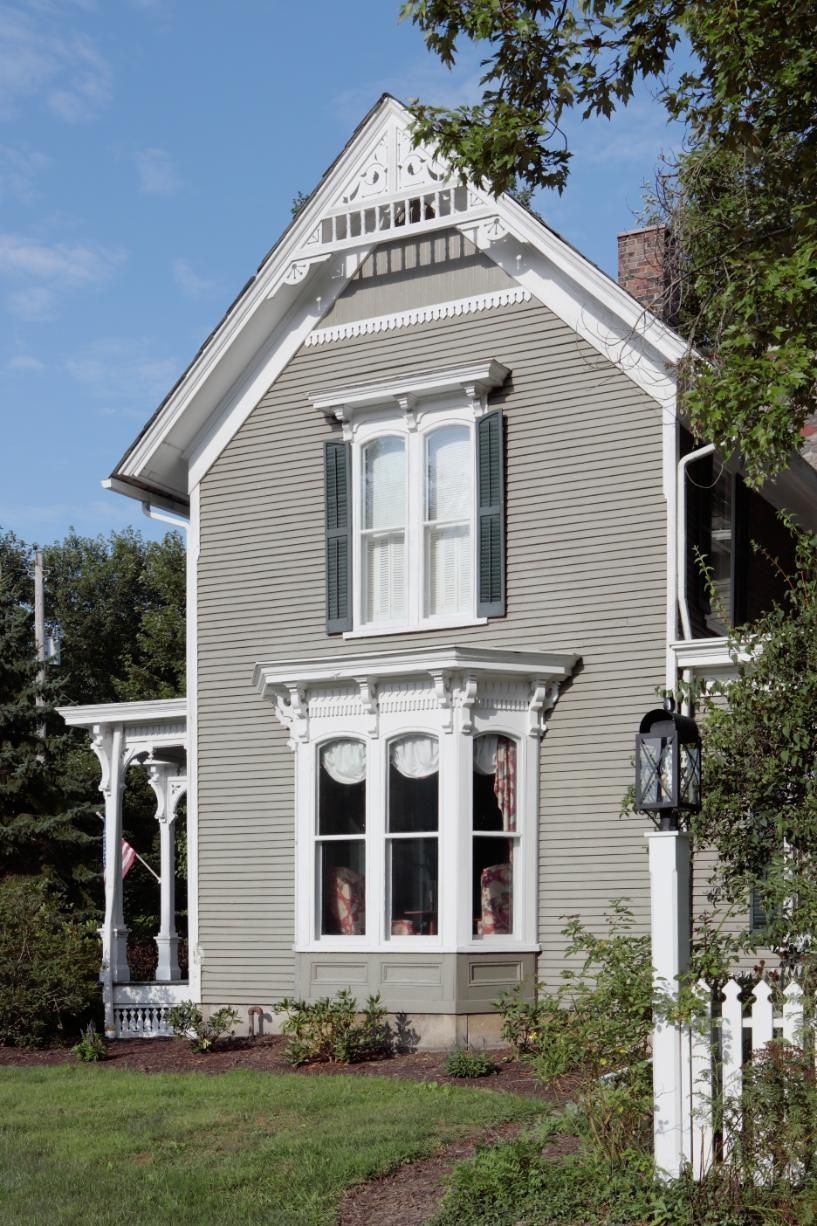 Victorian-style house with gray siding, white trim, and a small porch on a sunny day.