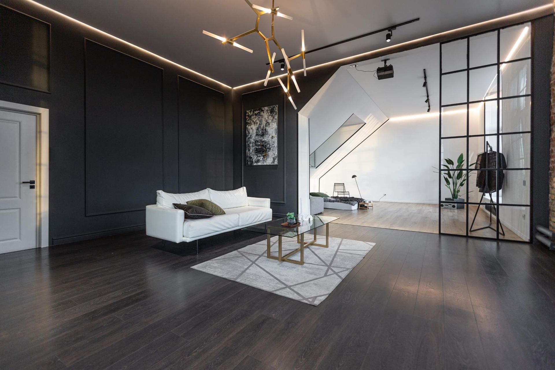 Modern loft interior with dark wood floors, white sofa, and geometric glass wall.