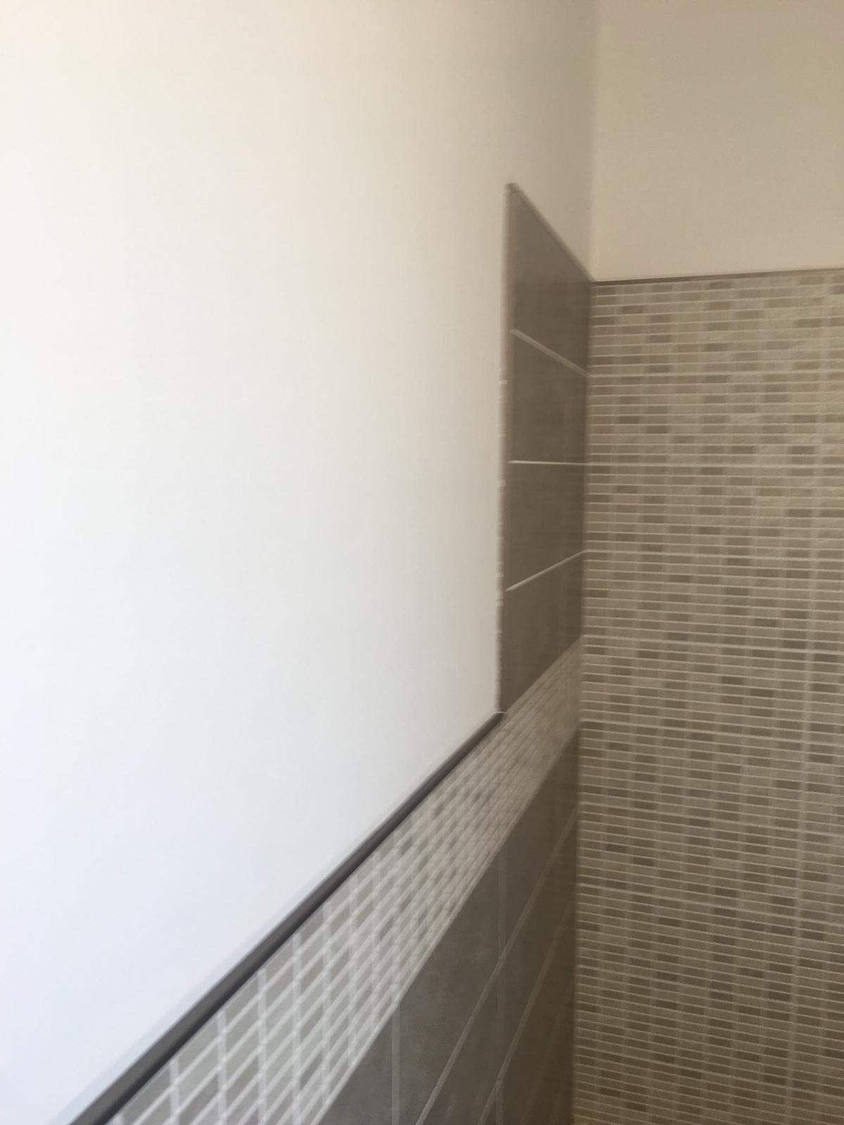 posa piastrelle sulla parete di un bagno