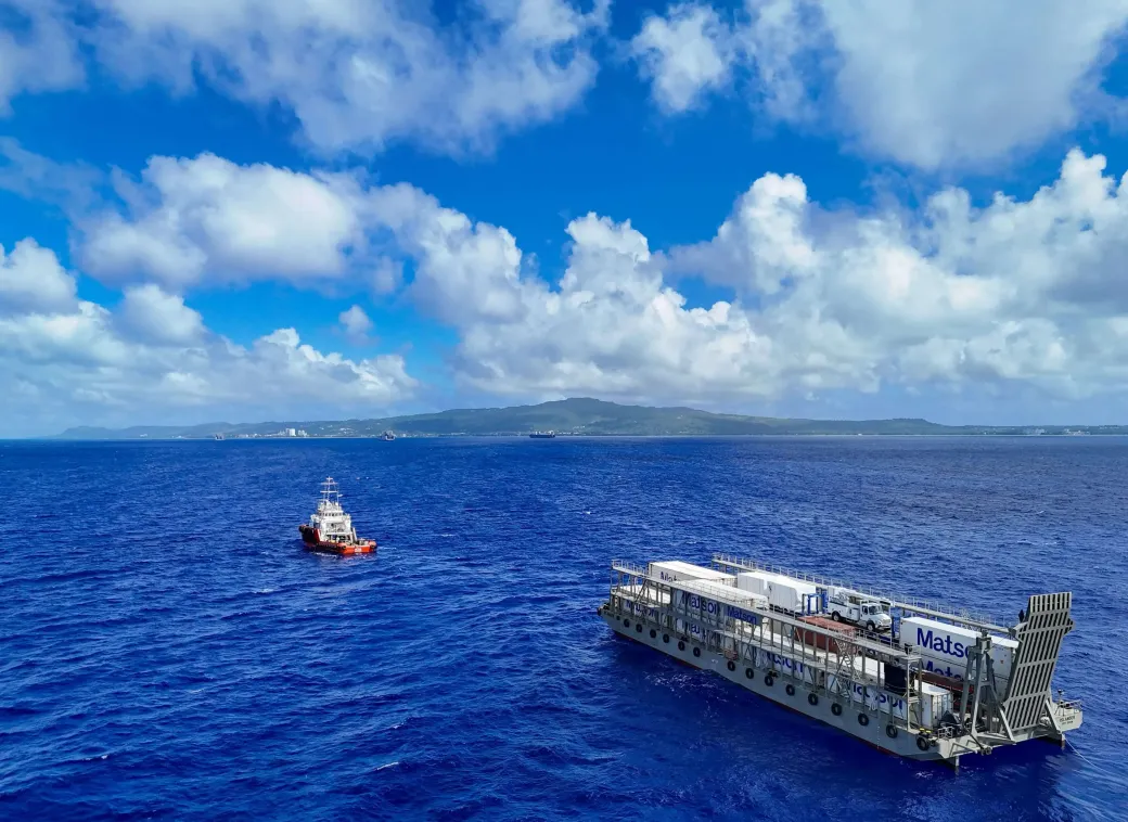 A large boat is floating on top of a large body of water towing a smaller boat.