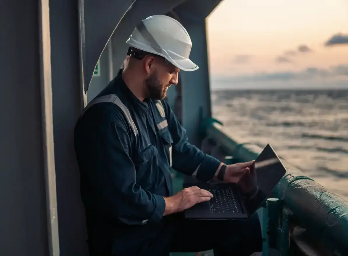 A man is sitting on a boat using a laptop computer.