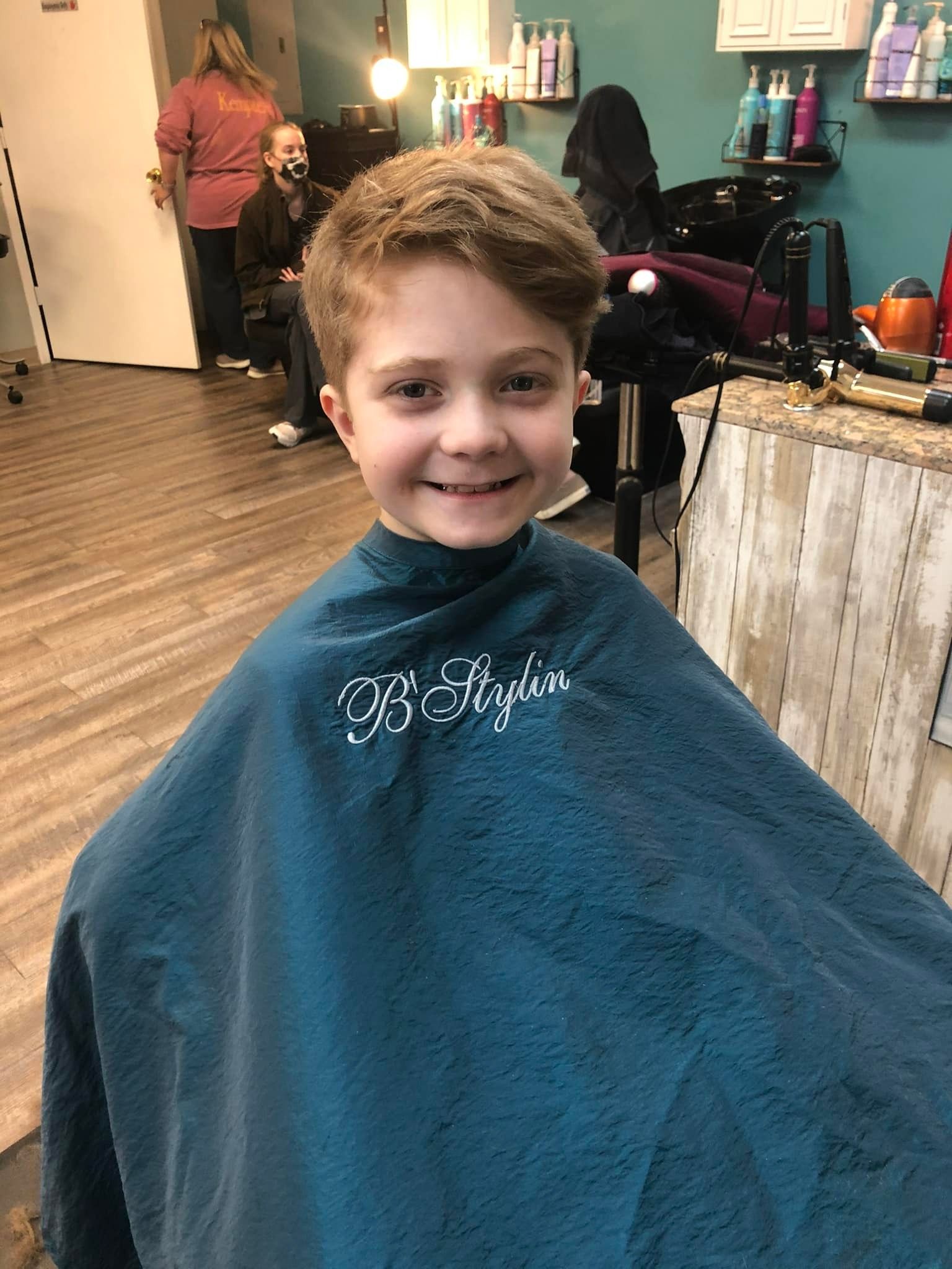 A young boy is getting his hair cut at a hair salon.
