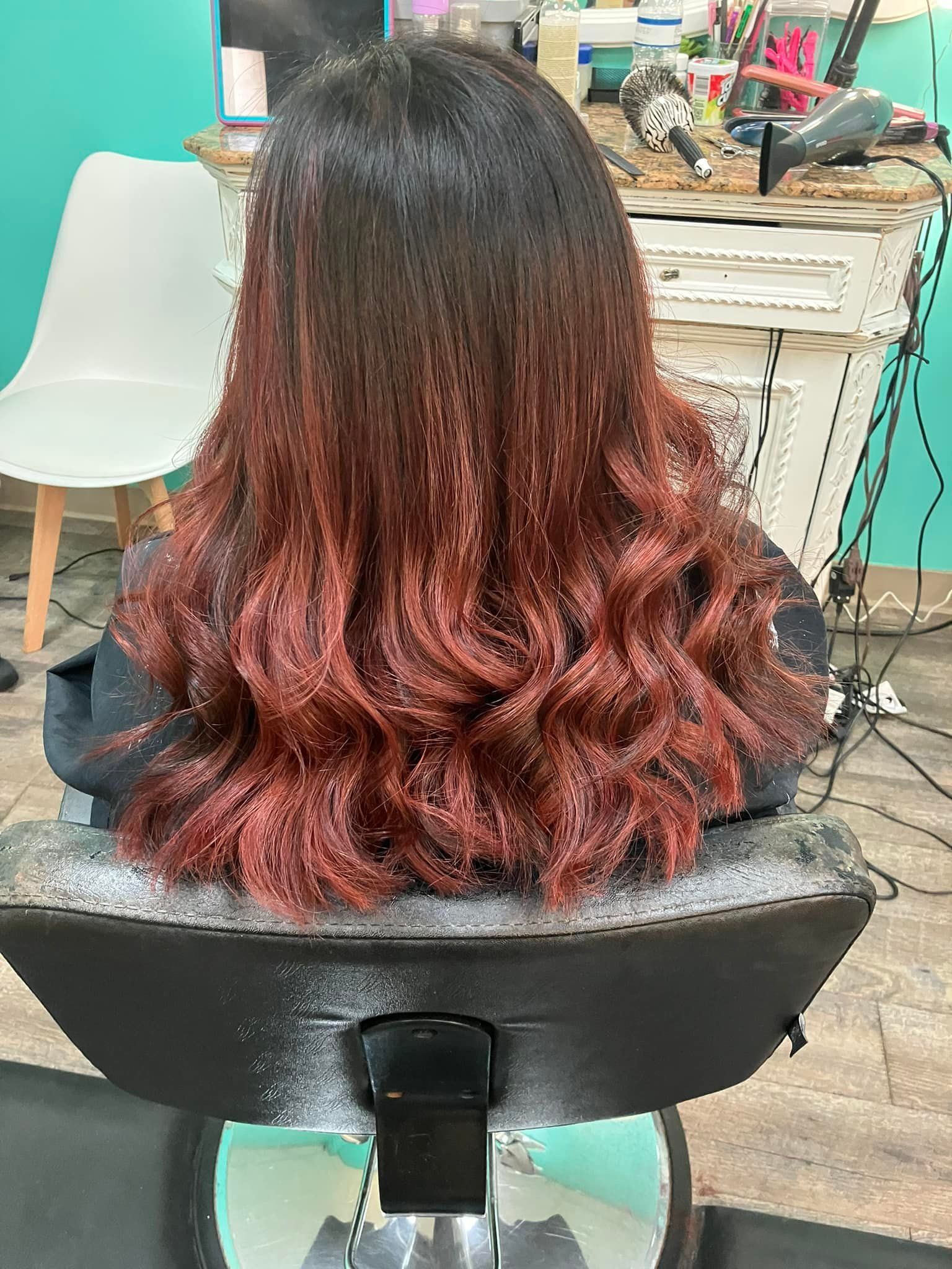 A woman with long red hair is sitting in a chair in a salon.