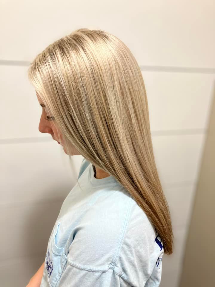 A woman with long blonde hair is wearing a blue shirt.