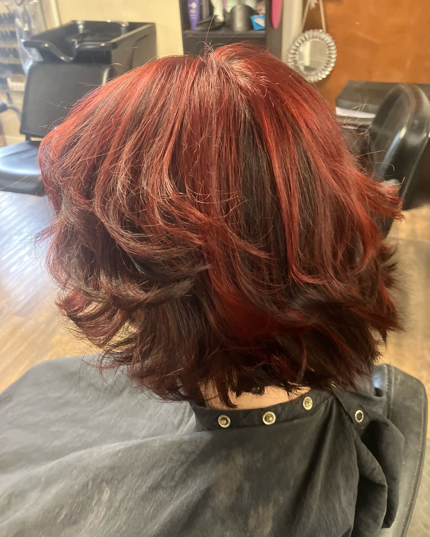 A woman with red hair is sitting in a chair in a salon.